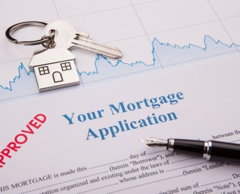 House key on a keychain and a pen laying on top of an approved mortgage loan application.